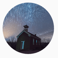 schoolhouse at night with star trails in the sky